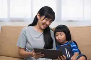 ibu mendampingi anak prasekolah memakai tablet keluarga sebagai tahap awal mengenalkan gadget untuk anak secara sehat.